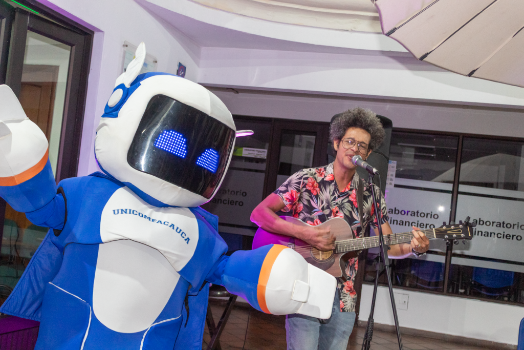 Nuestra mascota institucional TUni, posando al lado de Jorge Medina mientras él toca la guitarra.
