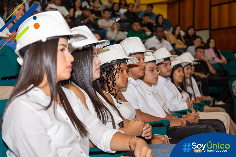 Estudiantes de décimo semestre sentados en el Auditorio atendiendo la ceremonia ya con sus cascos impuestos.
