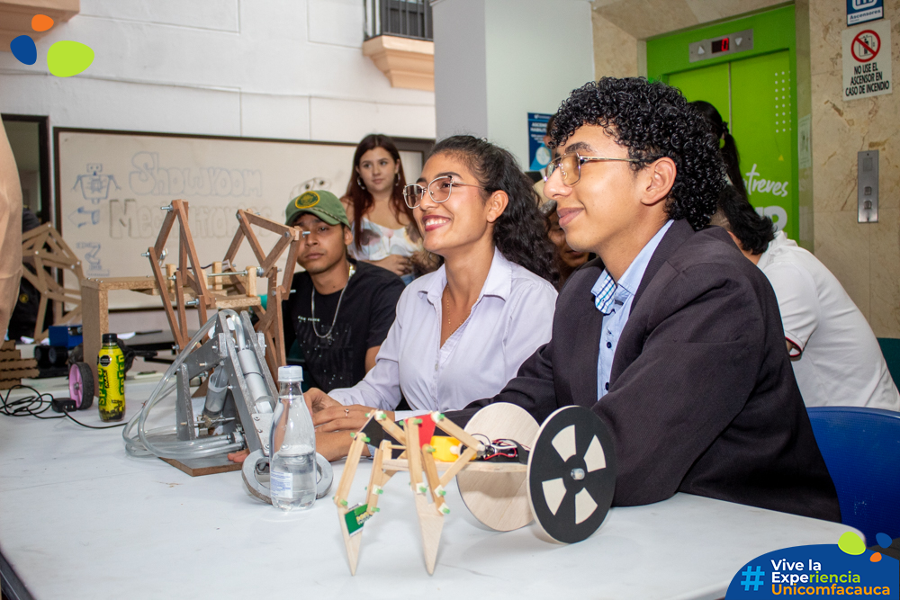 Dos chicos y una chica estudiante de Ingeniería Mecatrónica posando al lado de su proyecto en el Showroom Mechatronics.
